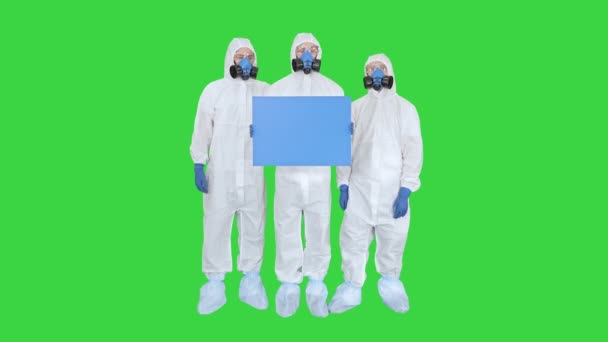 Drei Ärzte in Schutzanzügen halten weiße Tafel auf einem Green Screen, Chroma Key. — Stockvideo