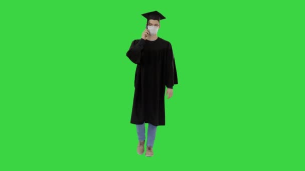 Joven estudiante de posgrado haciendo una llamada con teléfono inteligente con máscara médica en una pantalla verde, Chroma Key . — Vídeos de Stock