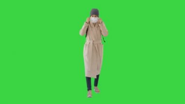 Paltolu bir kadın koruyucu yüz maskesi takıyor Yeşil Ekran 'da, Chroma Key.