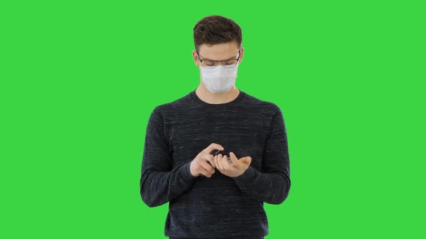 코로나 바이러스 인간 보호용 마스크를 쓰고 녹색 화면에서 세정제로 손을 닦고 있는 크로마키. — 비디오