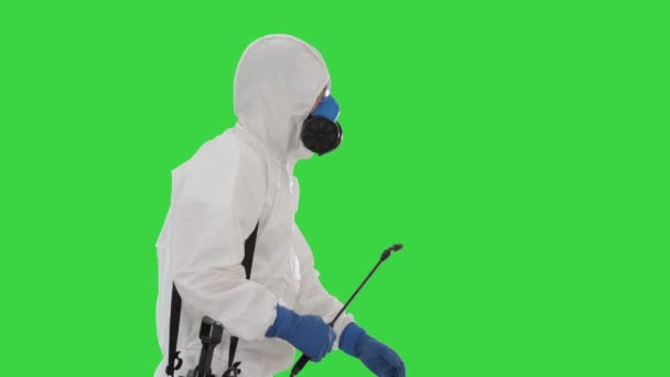 Lavoratore in tuta Hazmat e maschera di protezione del viso che cammina con attrezzature di disinfezione su uno schermo verde, chiave cromatica . — Video Stock