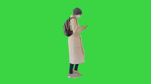 Kvinna bär medicinsk mask promenader på en grön skärm, Chroma Key. — Stockvideo