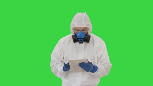 Епідеміолог у костюмі та масці дихальних шляхів, використовуючи цифрову табличку під час ходьби на зеленому екрані, Chroma Key. — стокове відео