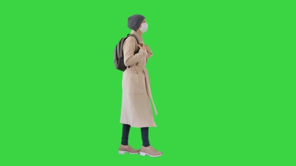 Covid-19 viruspreventie, vrouw met een medisch masker op haar gezicht lopend op een groen scherm, Chroma Key. — Stockvideo