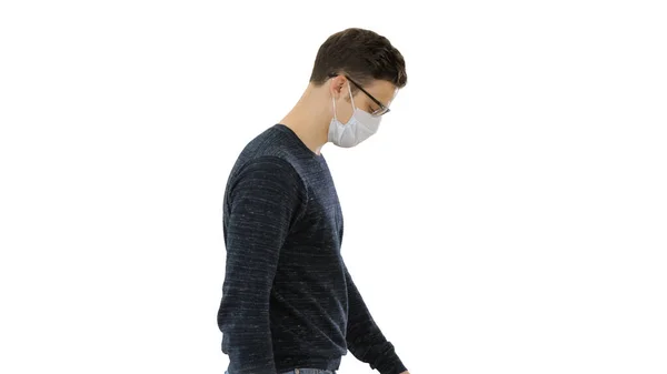 Молодой красивый мужчина ходит в медицинской маске на белом фоне . — стоковое фото