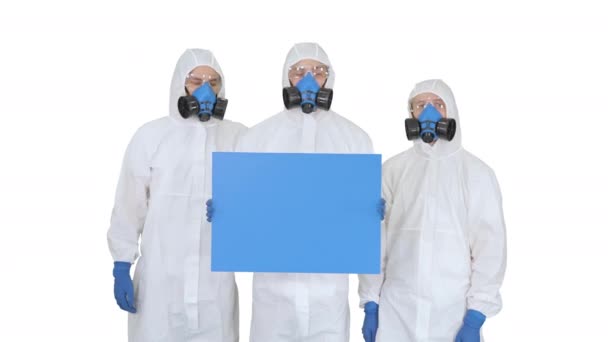 Drie artsen in beschermende pakken houden blanco boord op witte achtergrond. — Stockvideo