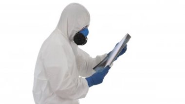 Koruyucu kıyafetli doktor beyaz arka planda yürürken akciğerlerinin röntgenine bakıyor..