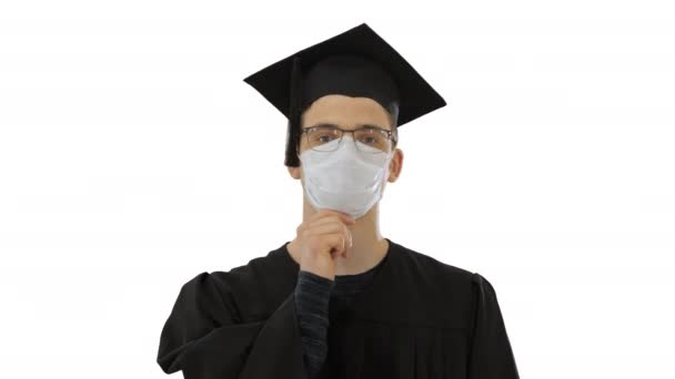 Studente laureato in una maschera medica a piedi su sfondo bianco . — Video Stock