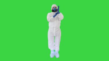 HAZMAT Giyen Adam Koruyucu Giysi Yeşil Ekran Krom Anahtar 'da Eldiven Giydiğini Gösteriyor.