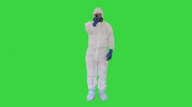 Koruyucu biyolojik tehlike kıyafetli doktor, yeşil ekran, Chroma Key 'deki 19 numaralı kontrol noktasında sıcaklığınızı ölçmek için lazer termometreyi gösteriyor..