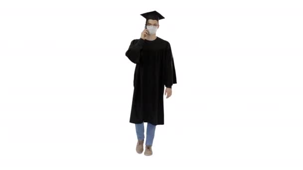 Молодой аспирант делает звонок со смартфона в медицинской маске на белом фоне . — стоковое видео