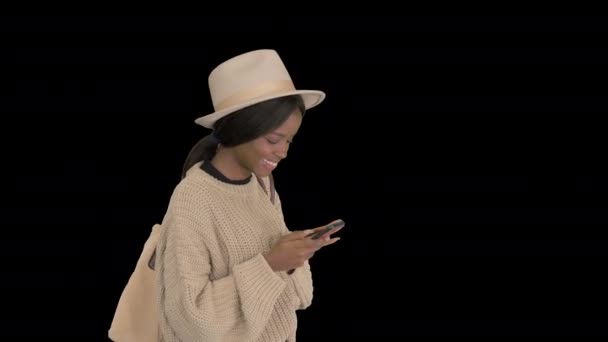 Afro-Amerikaanse vrouw met hoed, glimlachende sms 'jes op mobiele telefoon, Alpha Channel — Stockvideo