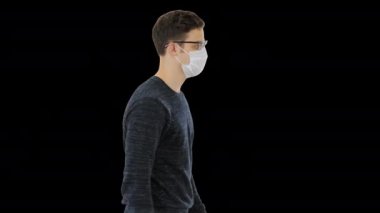Tıbbi maskeli genç yakışıklı adam Alpha Channel 'da yürüyor.