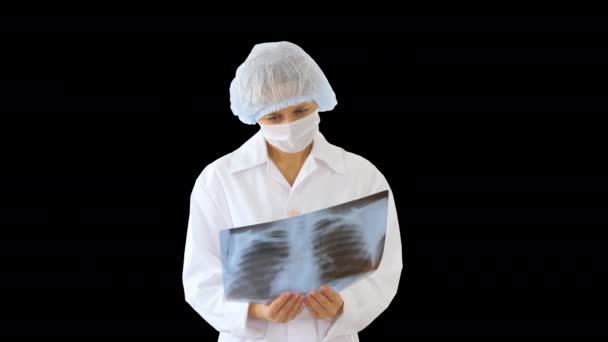 Orvosnő orvosi maszkot visel, röntgenképet néz, Alpha Channel — Stock videók