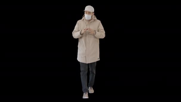 Uomo in costume invernale e maschera medica parlando con voi spiegando qualcosa mentre si cammina, Alpha Channel — Video Stock