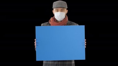 Moda kıyafetli ve tıbbi maskeli bir adam boş bir levha tutuyor, Alfa Kanalı.