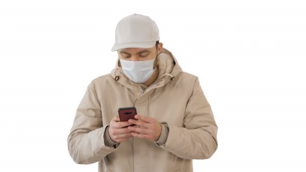 Joven hombre casual caminando haciendo una llamada usando ropa de abrigo y máscara protectora sobre fondo blanco . — Vídeos de Stock