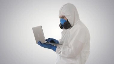 Beyaz koruyucu üniformalı bir doktor, gradyan arka planda dizüstü bilgisayar kullanıyor..