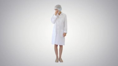 Diğerlerinin değişken arka planda enfeksiyon kapmasını önlemek için maskeli kadın doktor öksürüyor.