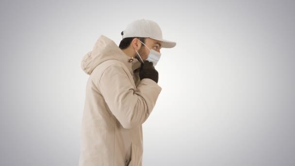 Winter-like dressed Caucasian man putting on medical mask on gradient background. — Stock Video