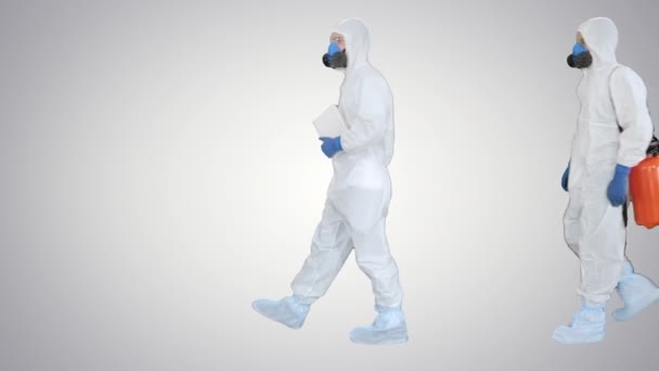 Drie desinfectoren lopen naar binnen en houden het desinfectiemiddel in hun handen op een hellende ondergrond. — Stockvideo