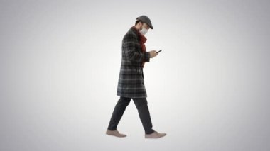 Tıbbi maskeli bir adam grafiksel arka planda yürüyor ve cep telefonu kullanıyor..