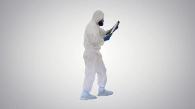 Koruyucu kıyafetli doktor, arka planda yürürken akciğerlerinin röntgenine bakıyor..