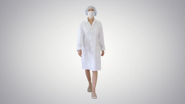 Walking female doctor wearing surgical mask on gradient background. — Stock Video