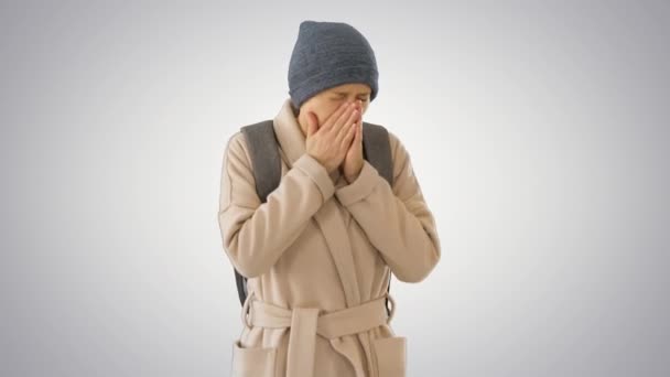Vrouw in een jas wandelen en hoesten op gradiënt achtergrond. — Stockvideo