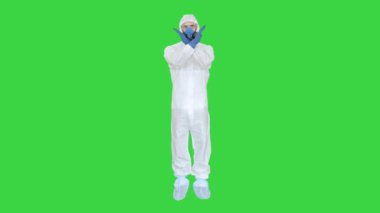 Koruyucu maske takan ve tehlikeli madde giysisi giyen bir adam el ele tutuşup Yeşil Ekran 'da, Chroma Key' de dur işareti yapıyor..