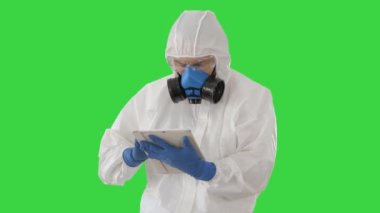 Koruyucu kıyafetli bir erkek doktor yeşil ekranda dijital tablet kullanıyor, Chroma Key.