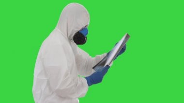 Koruyucu kıyafetli doktor yeşil ekranda yürürken akciğerlerinin röntgenine bakıyor..