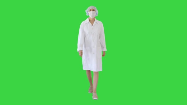 緑の画面上に外科マスクを身に着けている女性医師を歩く,クロマキー. — ストック動画
