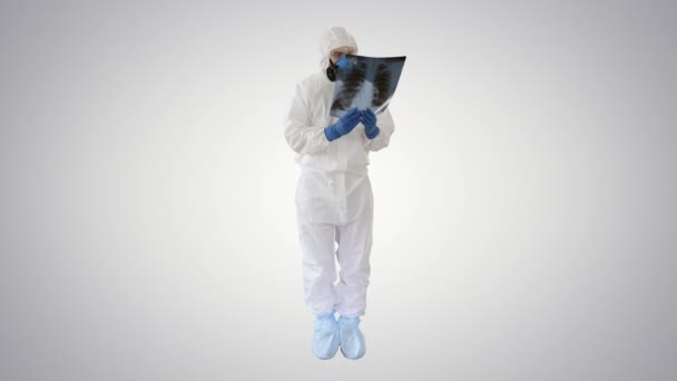 Infectious disease doctor in protective antibacterial suit and medical mask Pulmonologist examines an x-ray of lungs on gradient background. — Stock Video