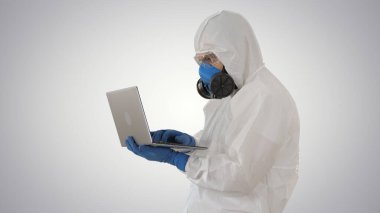 Beyaz koruyucu üniformalı bir doktor, gradyan arka planda dizüstü bilgisayar kullanıyor..