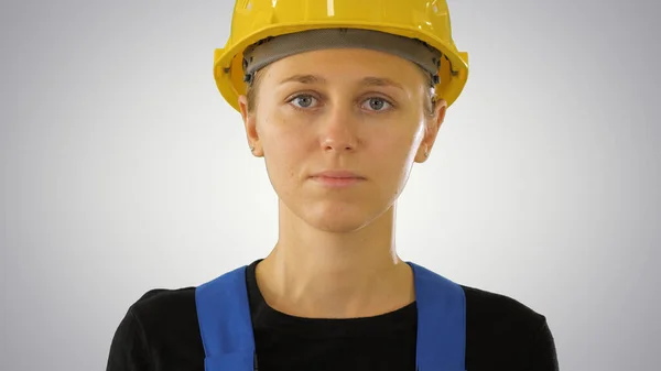 Молода приваблива кавказька жінка-будівельник у твердому жовтому шоломі на градієнтному фоні . — стокове фото