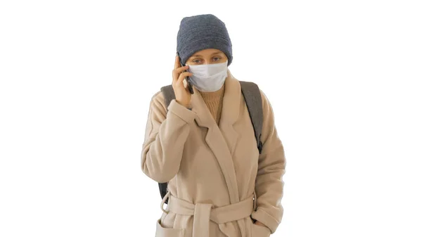 Meisje met een beschermend masker lopen en het maken van een telefoontje op de telefoon op witte achtergrond. — Stockfoto