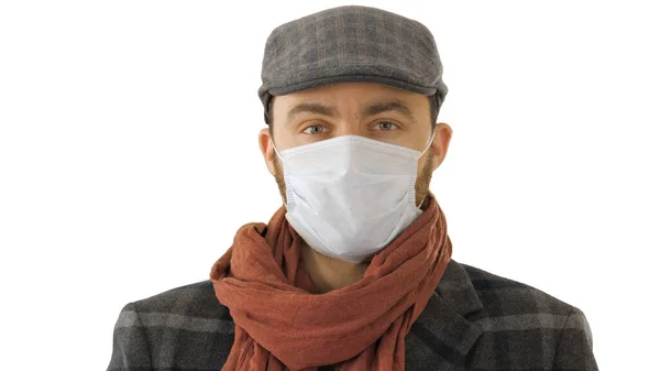 Handsome young European man in trendy coat wearing disposable protective face mask on white background. — Stock Photo, Image