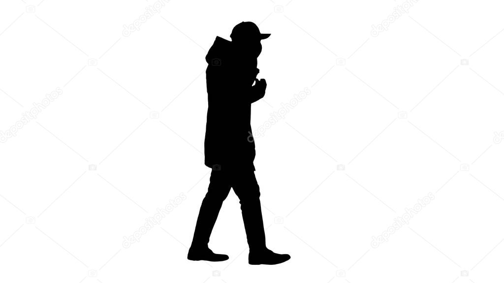 Silhouette Man wears protective medical mask and talks on the phone walking.