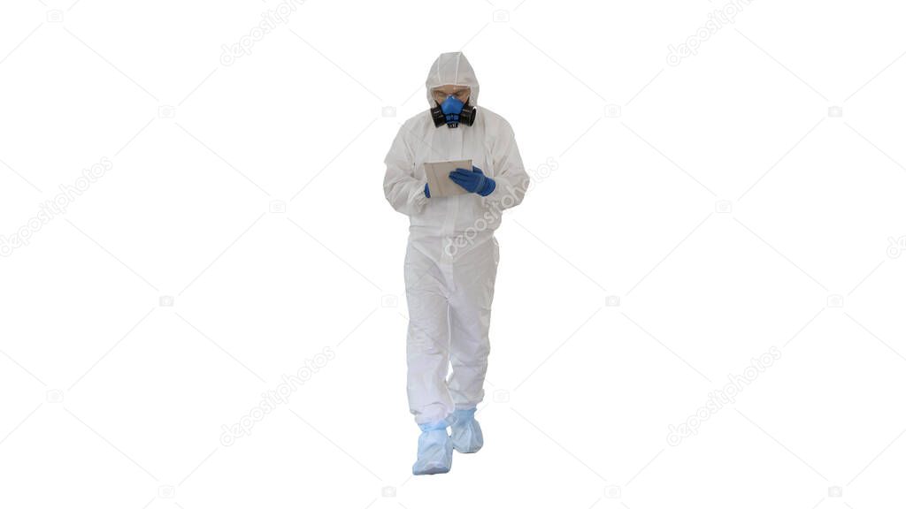 Epidemiologist in hazmat suit and respirator mask using digital tablet while walking on white background.