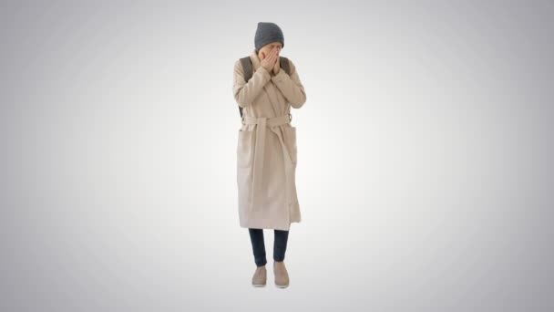 Женщина в пальто ходит и кашляет на градиентном фоне . — стоковое видео