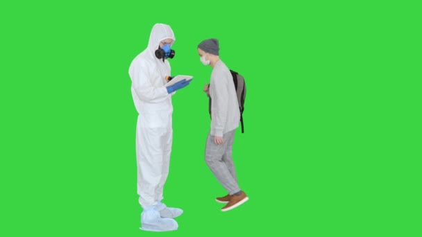 Man in hazmat pak het controleren van de temperatuur en het stoppen van de vrouw op een groen scherm, Chroma Key. — Stockvideo