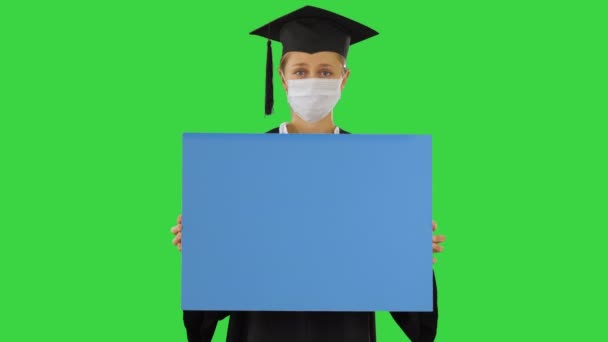 Graduate student girl in protection mask holding blank board on a Green Screen, Chroma Key. — Stock Video