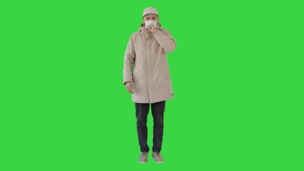 身穿高档服装，戴着一次性医疗口罩，在绿色屏风上咳嗽的男人，铬钥匙. — 图库视频影像
