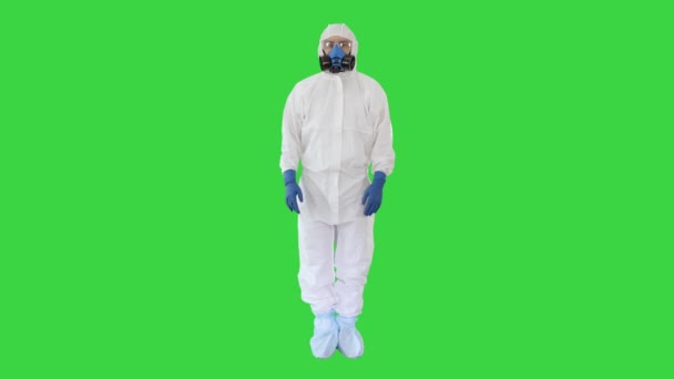 博士または危険スーツの科学者は、緑の画面、クロマキーの側面に想像上のオブジェクトを指す何かを提示. — ストック動画