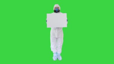 Güvenlik giysisi içindeki bilim adamı yeşil ekranda boş beyaz tahta tutuyor, Chroma Key..