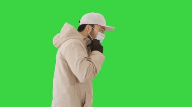 Kışlık beyaz bir adam yeşil ekranda tıbbi maske takıyor, Chroma Key.