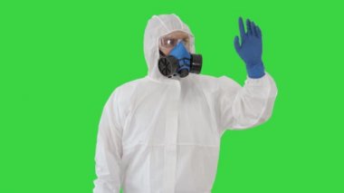 Hazamat giysileri içindeki tıp doktoru Yeşil Ekran 'da hayali bir ekrana işaret ediyor, Chroma Key.
