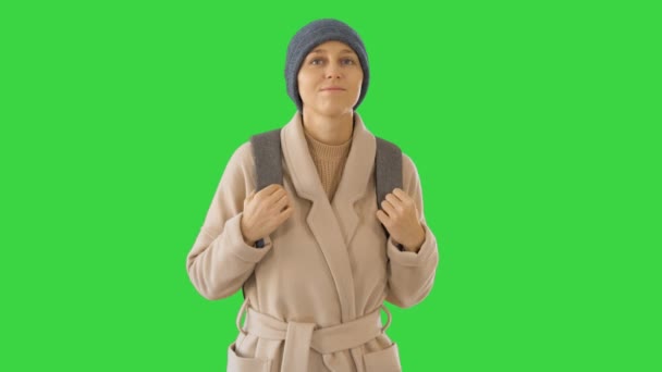 Jonge vrouw draagt jas en rugzak lopen op een groen scherm, Chroma Key. — Stockvideo
