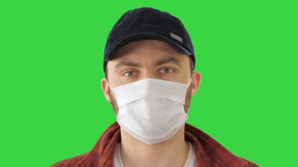 Молода людина жестикулює і носить маску, показуючи її на зеленому екрані, Chroma Key. — стокове відео